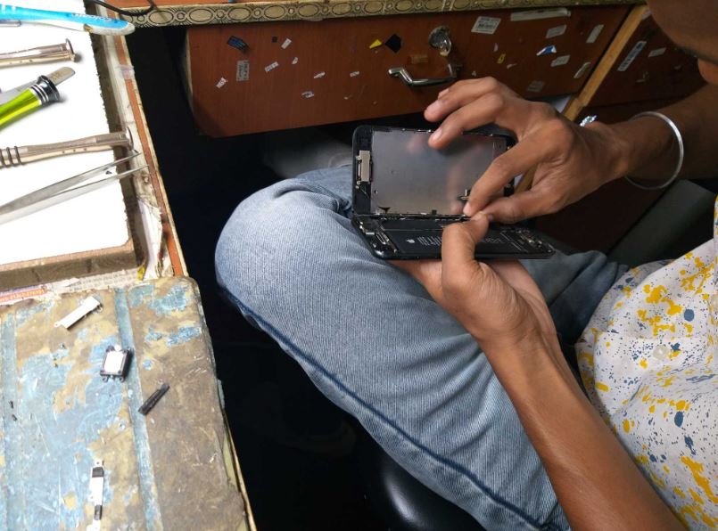 Solutionhubtech technician carefully removing iPhone screen assembly with precision tools — iPhone repair in Kashmiri Gate