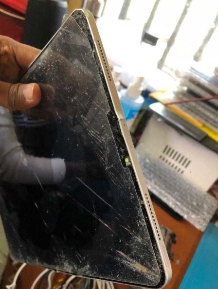 iPad Pro with severely scratched and cracked screen edge being held for assessment — iPad Pro screen repair in Vaishali at Solutionhubtech